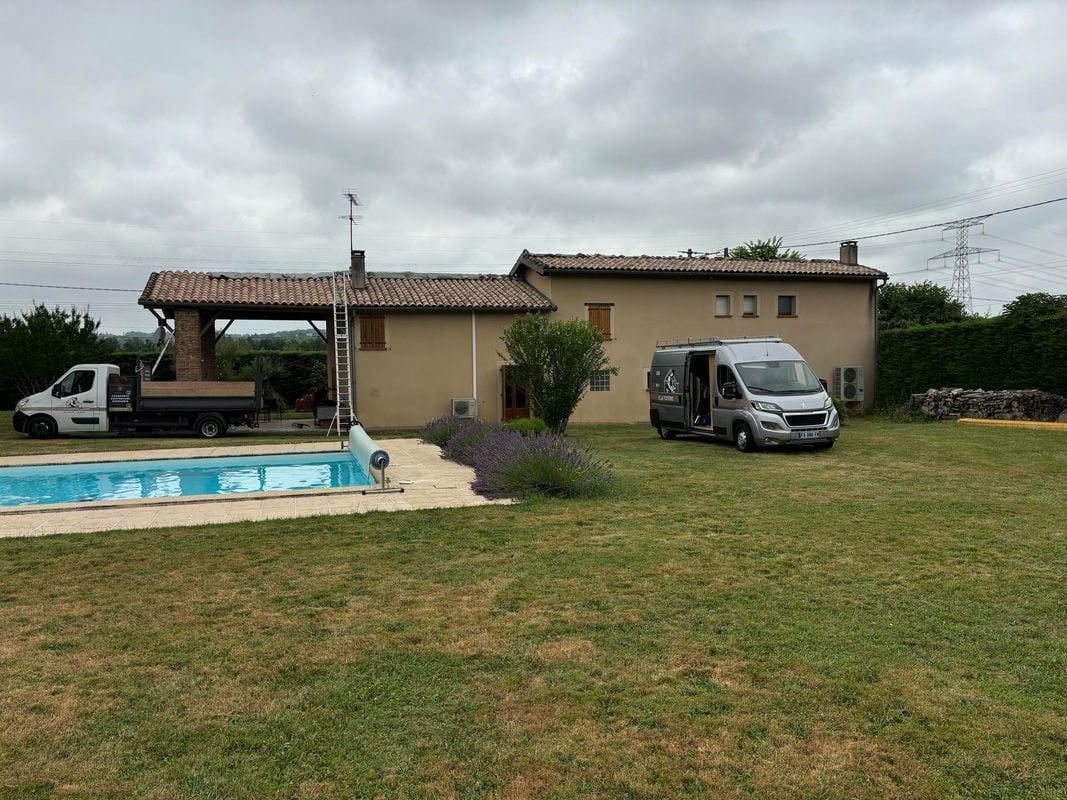 Une maison avec le véhicule de l'entreprise garé devant et une échelle grimpant jusqu'au toit