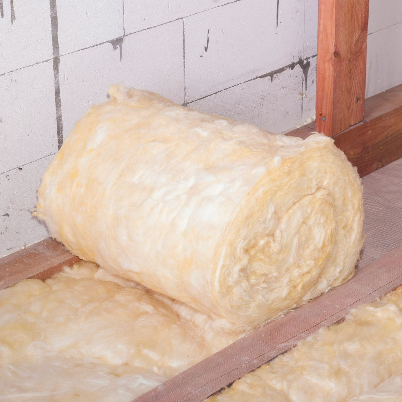 Un rouleau d'isolant posé sur le plancher de combles