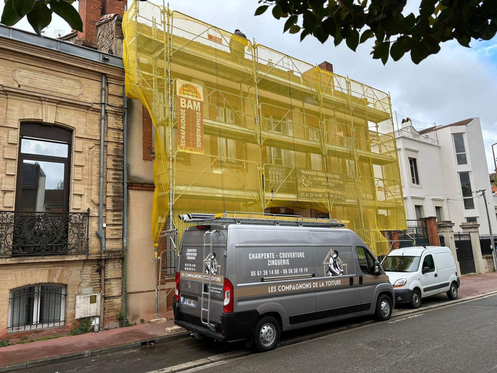 Une maison avec le véhicule de l'entreprise garé devant et un échafaudage