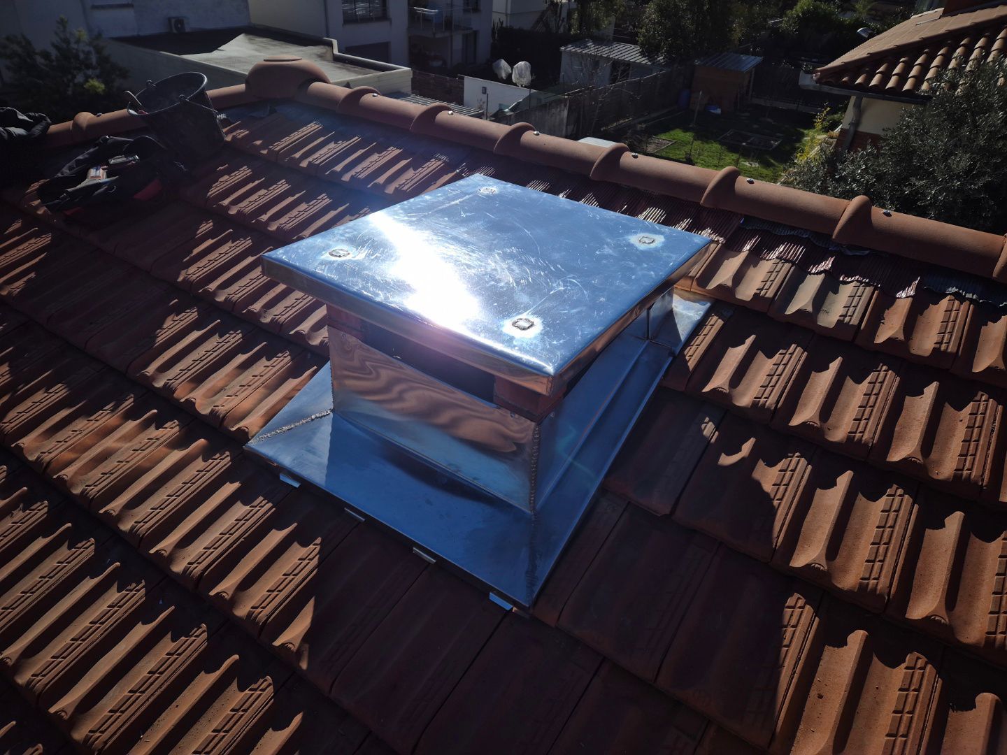 Une cheminée en zinc sur un toit en tuiles