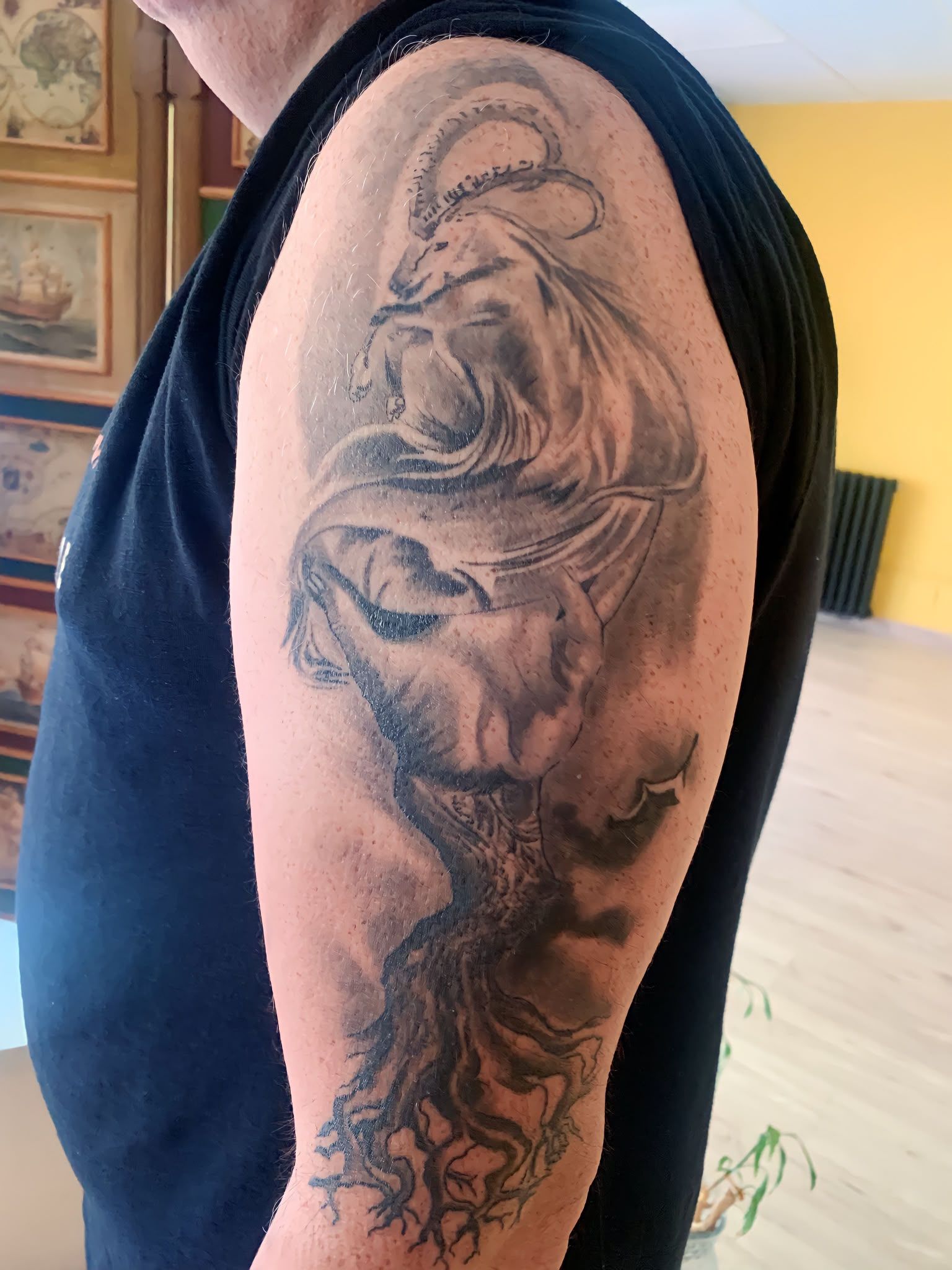 Primer plano de la parte superior de un brazo tatuado con un diseño de león en negro y gris, en interiores