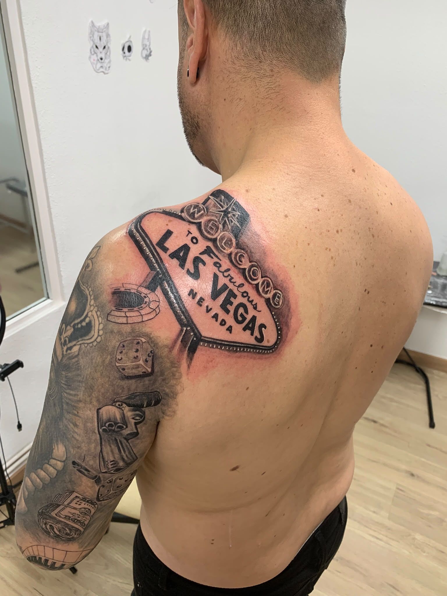 Vista desde atrás de una persona sin camiseta, con un tatuaje grande en el hombro y la parte superior del brazo