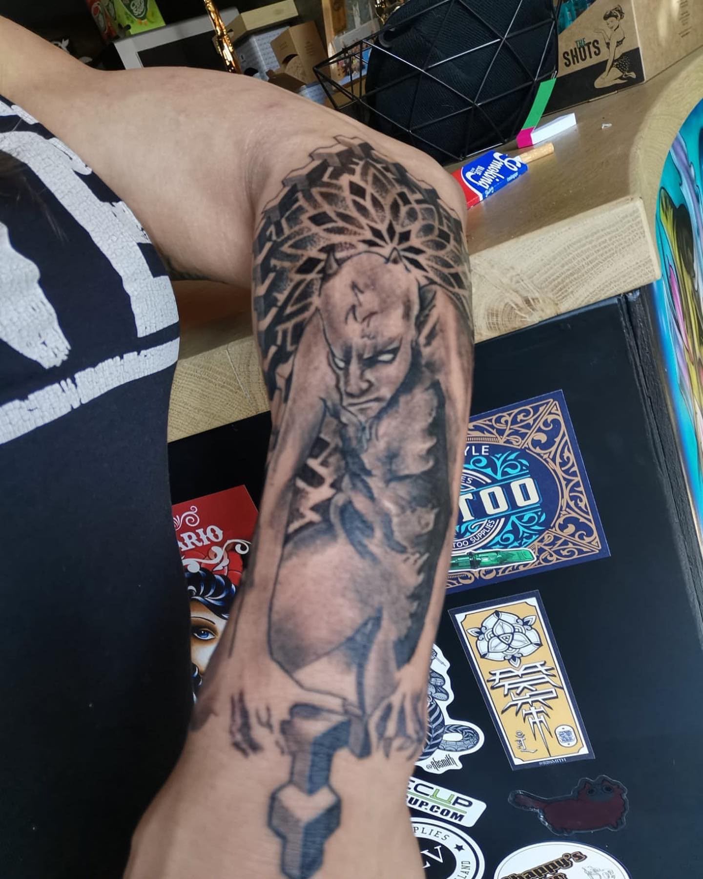 Antebrazo tatuado con un retrato en escala de grises y un diseño floral en un estudio de tatuajes.