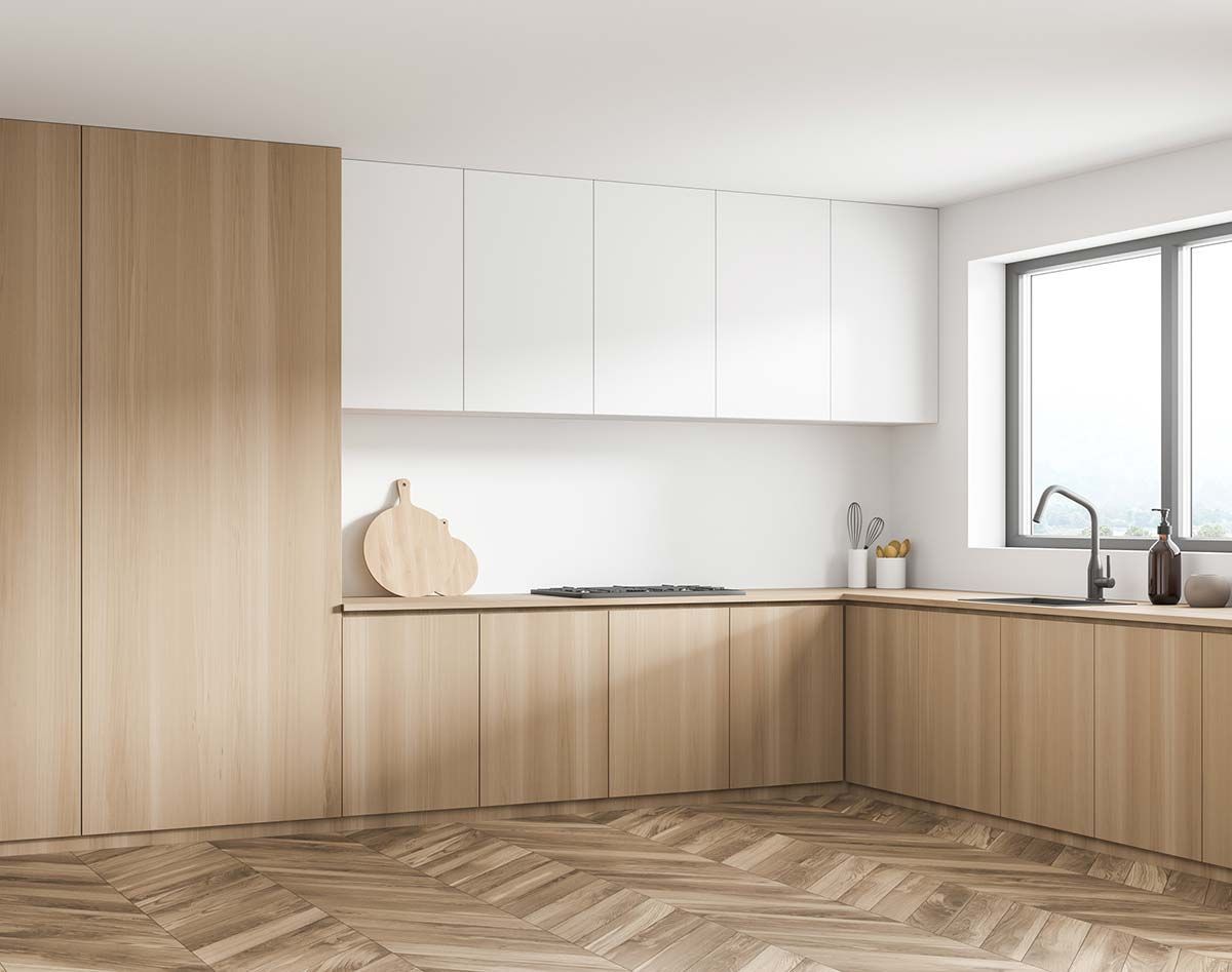 Cocina moderna con gabinetes de madera clara, gabinetes superiores blancos y piso en espiga.