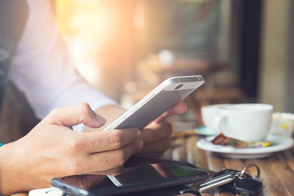 Eine Person sitzt an einem Tisch und telefoniert mit einem Mobiltelefon.