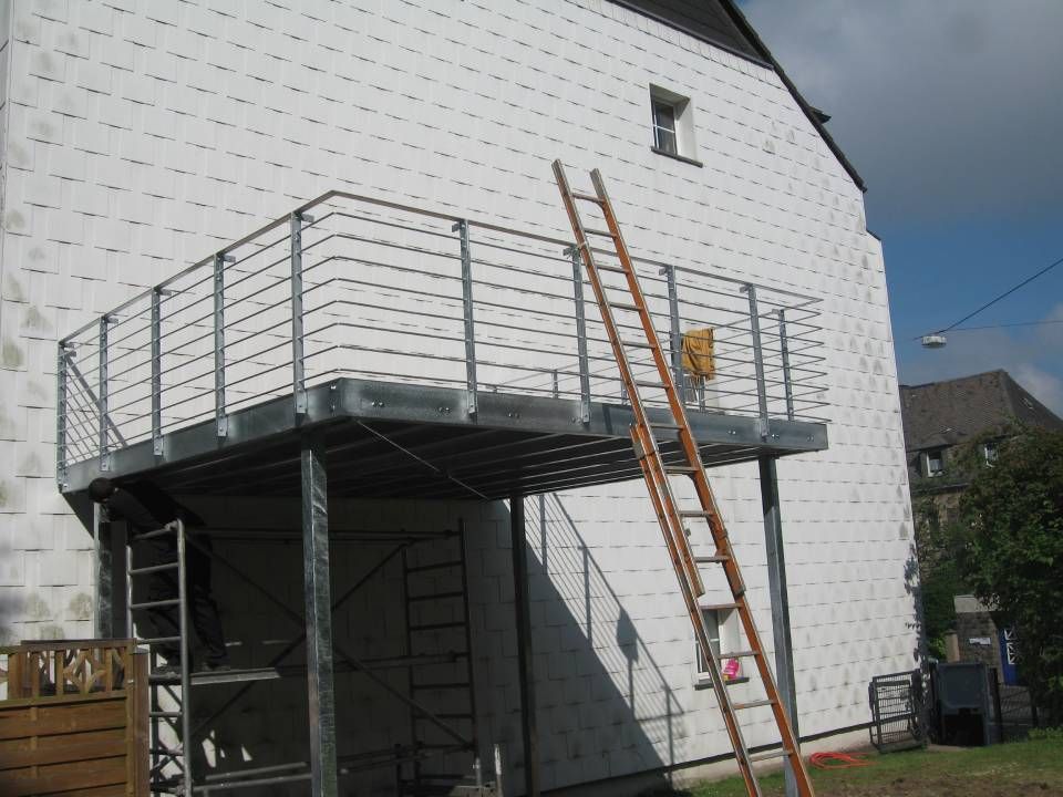 Metallgeländer an einem Balkon mit angelehnter Holzleiter