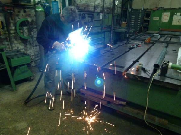 Person arbeitet mit einem Schweißgerät in einer Werkstatt