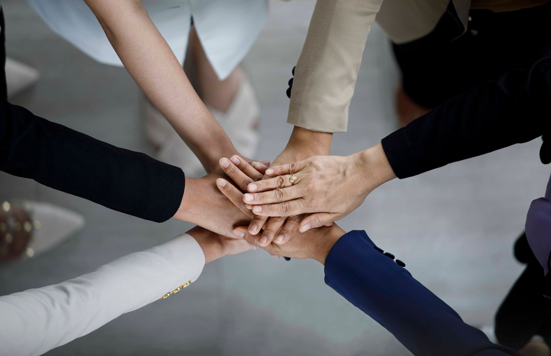 Die Hände mehrerer Personen bilden einen Kreis und symbolisieren Teamwork und Zusammenarbeit.