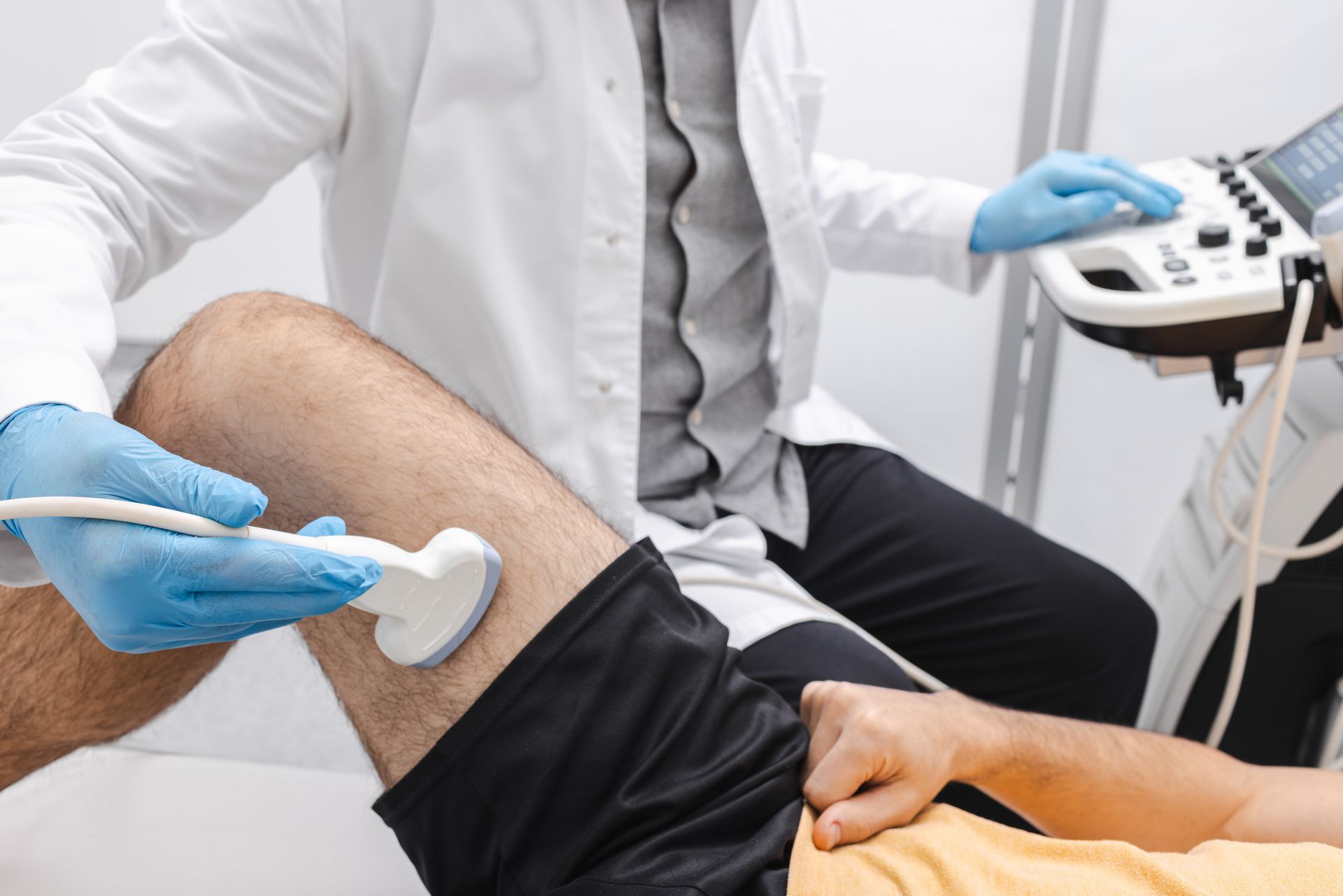 ein Doktor untersucht per Ultraschall den Oberschenkel eines Patienten