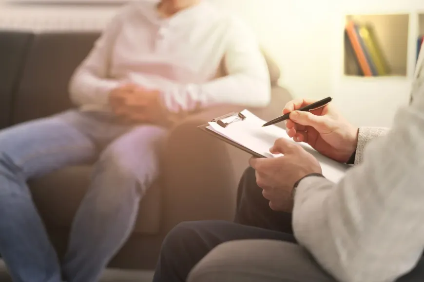 Terapeuta tomando notas durante una sesión con una persona sentada en un diván.