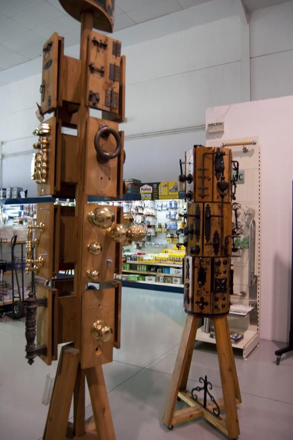 Expositores de herrajes para puertas en una ferretería. Estructuras de madera que albergan diversos pomos, manijas y cerraduras.