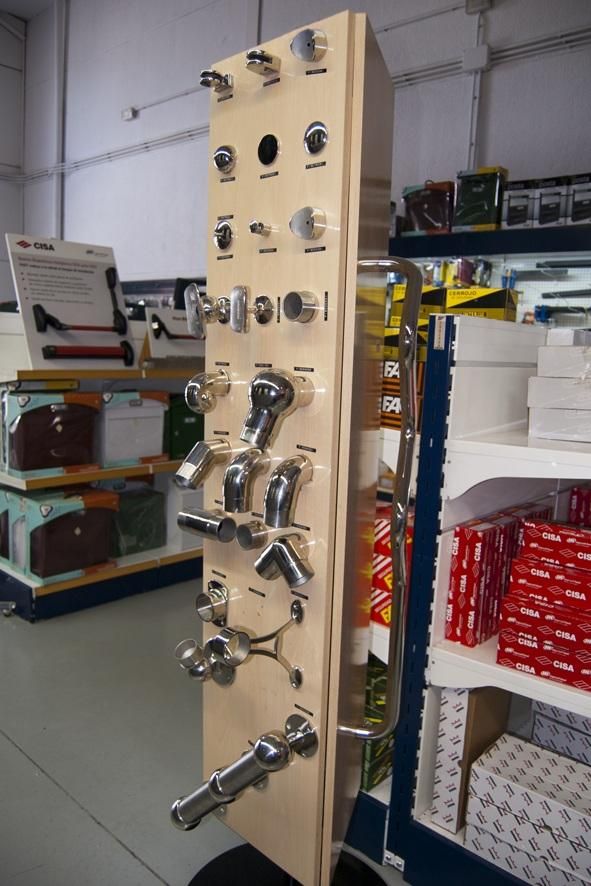 Expositor que muestra diversos accesorios de baño cromados en una ferretería.