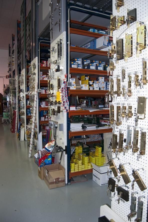 Interior de ferretería con estantes y exhibidores de herrajes para puertas y otros suministros.