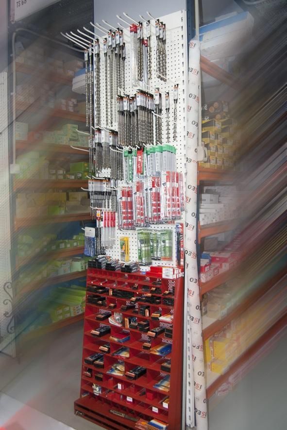 Exhibición de herramientas y ferretería en el pasillo de una tienda, incluidos taladros, conectores y artículos empaquetados.