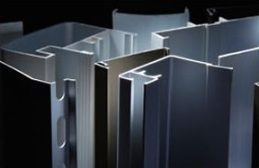 Extrusiones de aluminio surtidas, de varias formas y tamaños, sobre un fondo oscuro.