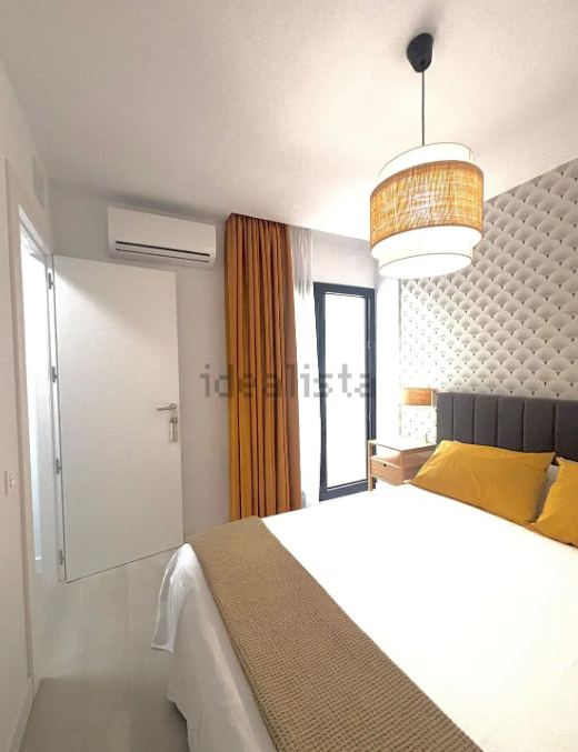 Dormitorio con cortinas amarillas, cama y lámpara decorativa.