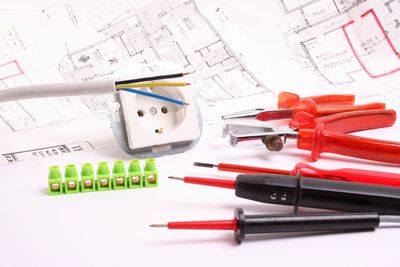 Techniker prüft die elektrische Verkabelung in einem Schaltschrank mit einem digitalen Messgerät.