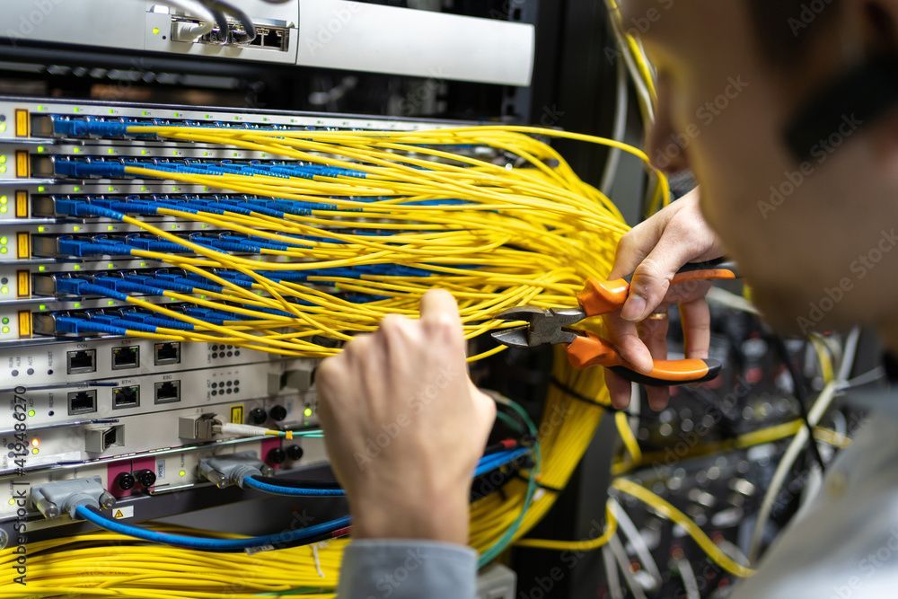 Techniker verbindet gelbe Glasfaserkabel in einem Netzwerkserverschrank