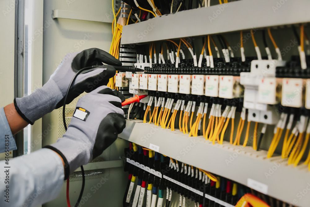 Behandschuhte Hände verkabeln einen Serverschrank mit gelben und schwarzen Kabeln in einem Verteilerkasten.