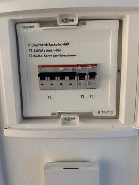Behandschuhte Hände verkabeln einen Serverschrank mit gelben und schwarzen Kabeln in einem Verteilerkasten.