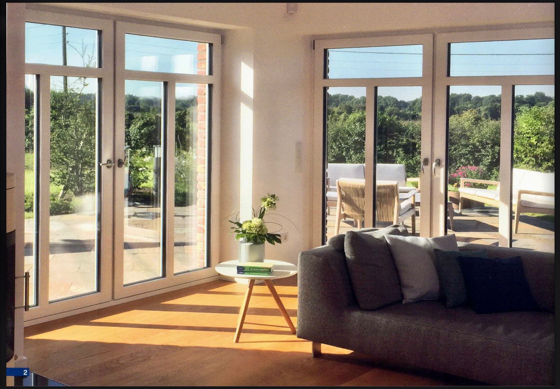 Lichtdurchflutetes Wohnzimmer mit großen, weiß gerahmten Fenstern