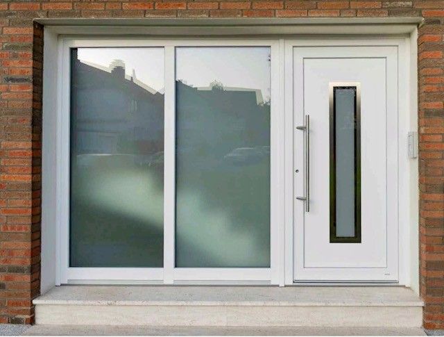 Weiße Eingangstür mit Seitenfenster, modernes Design, in einem Backsteingebäude.