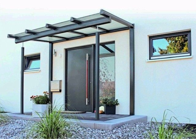 Moderner Hauseingang mit grauer Tür, Markise und kleinen Fenstern.