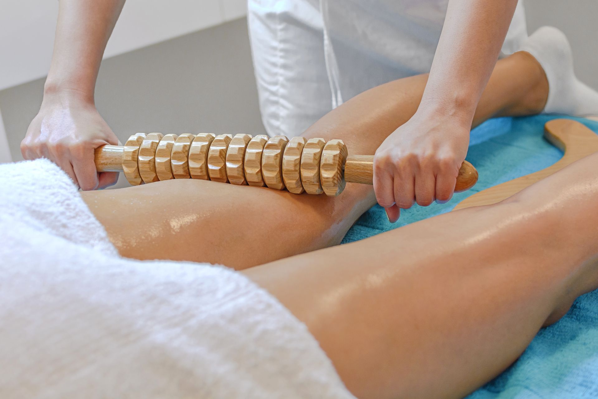 Lors d'un soin au spa, un thérapeute fait rouler un masque en bois sur le bas du dos nu d'un client.