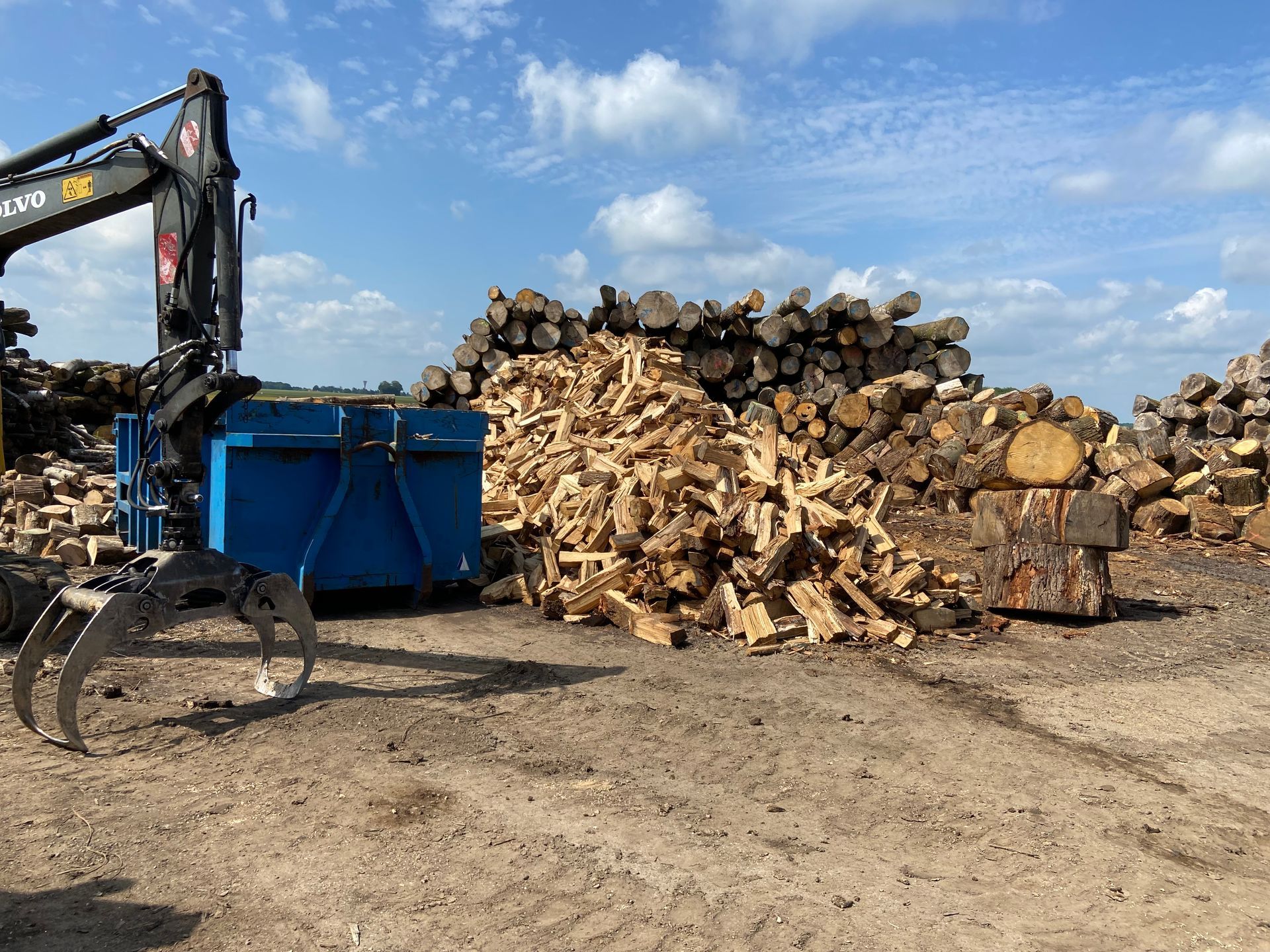 Des stères de bois empilés à côté d'une benne