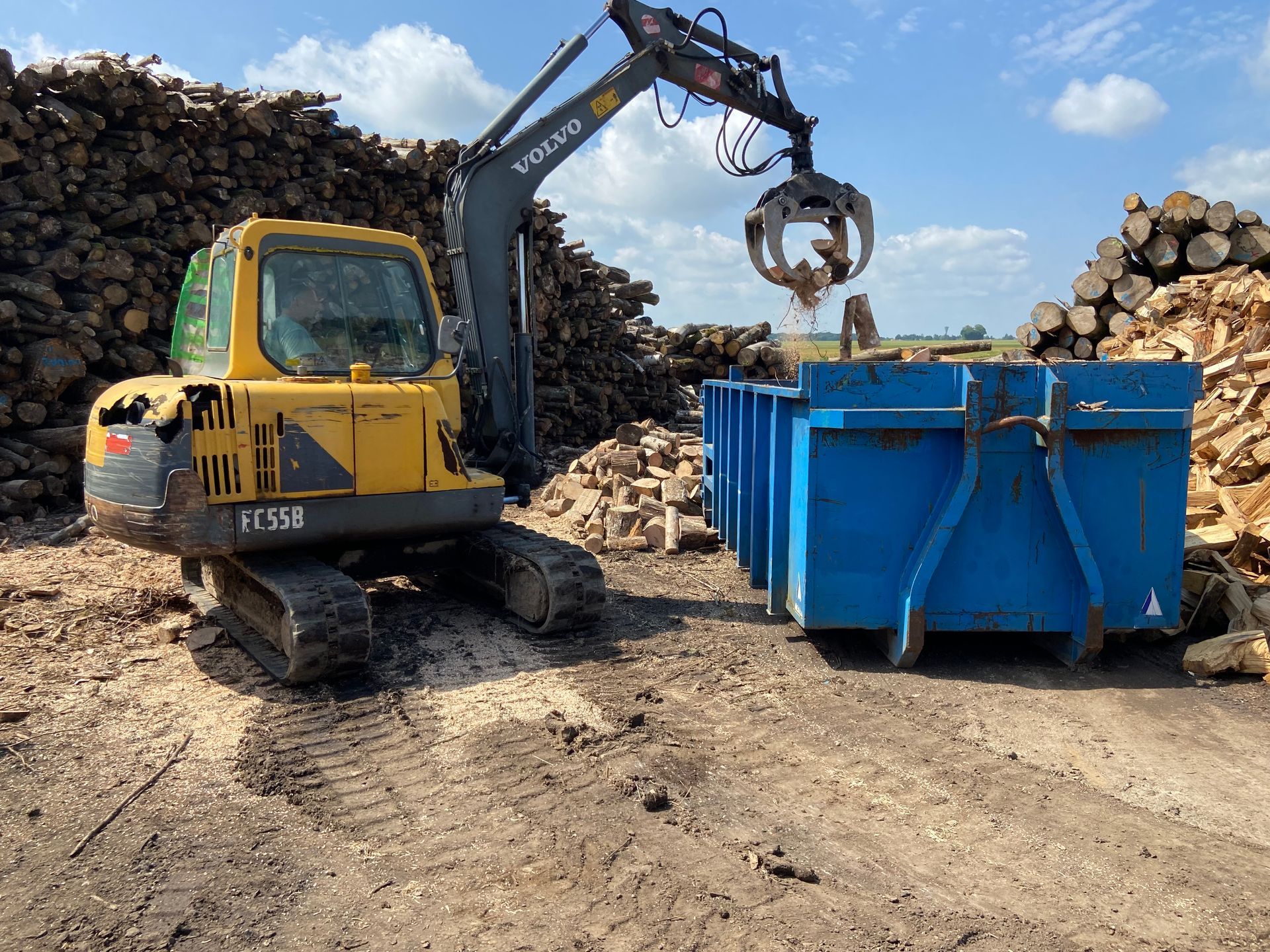 Chargement de bois dans un container par un engin
