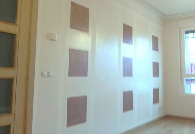 Una habitación con paredes blancas y cuadrados marrones.