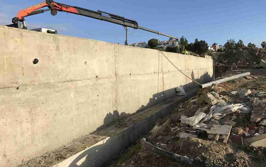 Se está construyendo un gran muro de hormigón con una grúa fijada al mismo.