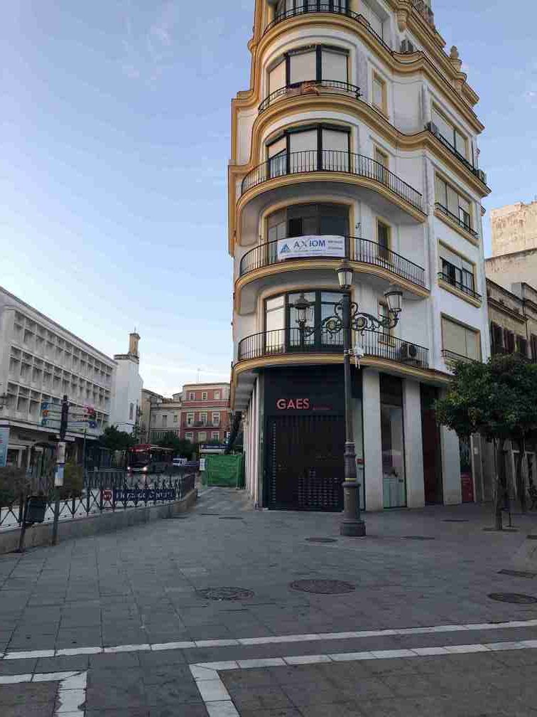 Un edificio muy alto con muchas ventanas está situado en la esquina de una calle de la ciudad.