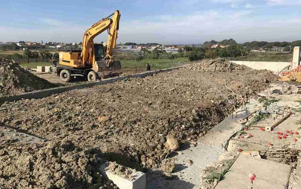 Una excavadora amarilla está moviendo tierra en un sitio de construcción.