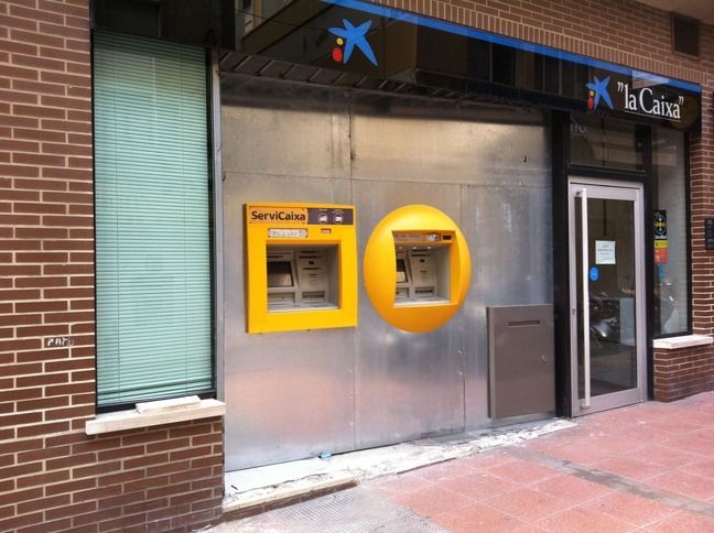 Un edificio de ladrillos con un cajero automático amarillo enfrente.