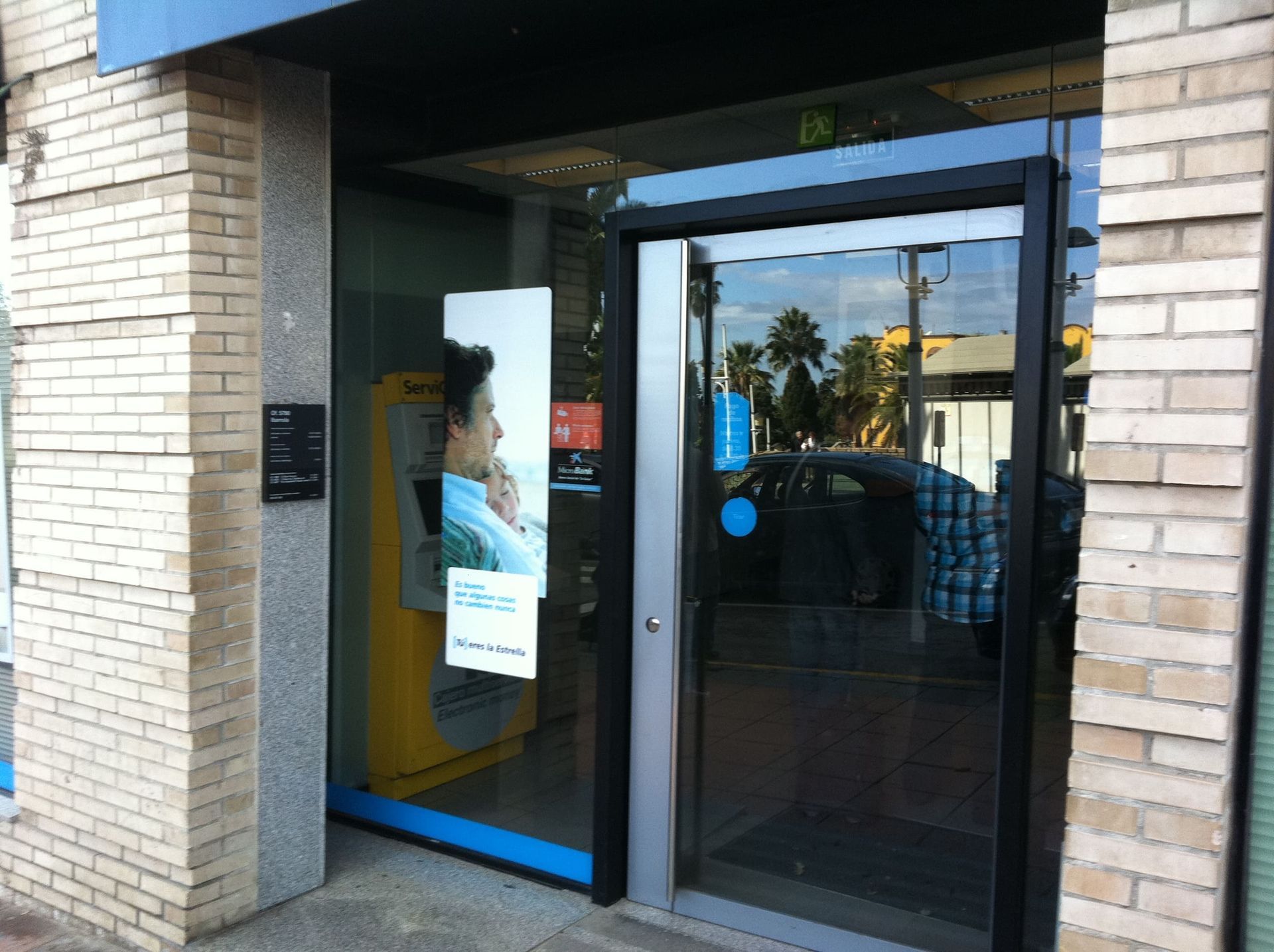 Un edificio de ladrillo con una puerta de vidrio y un cajero automático amarillo.