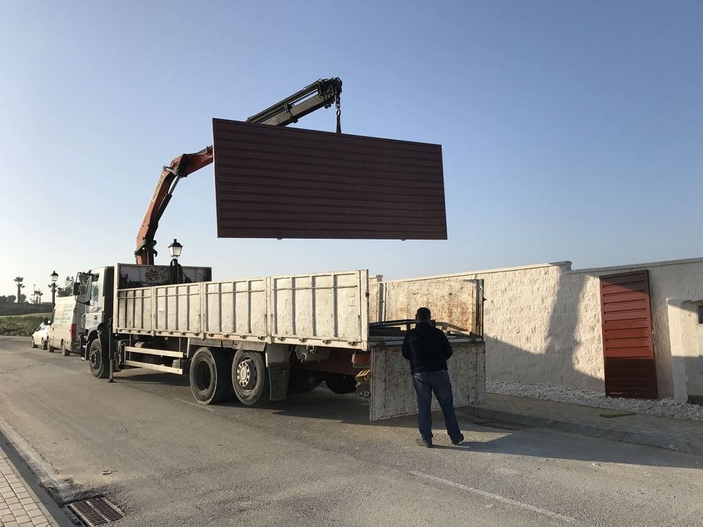 Un hombre está de pie junto a un camión que está levantando una gran pieza de metal.