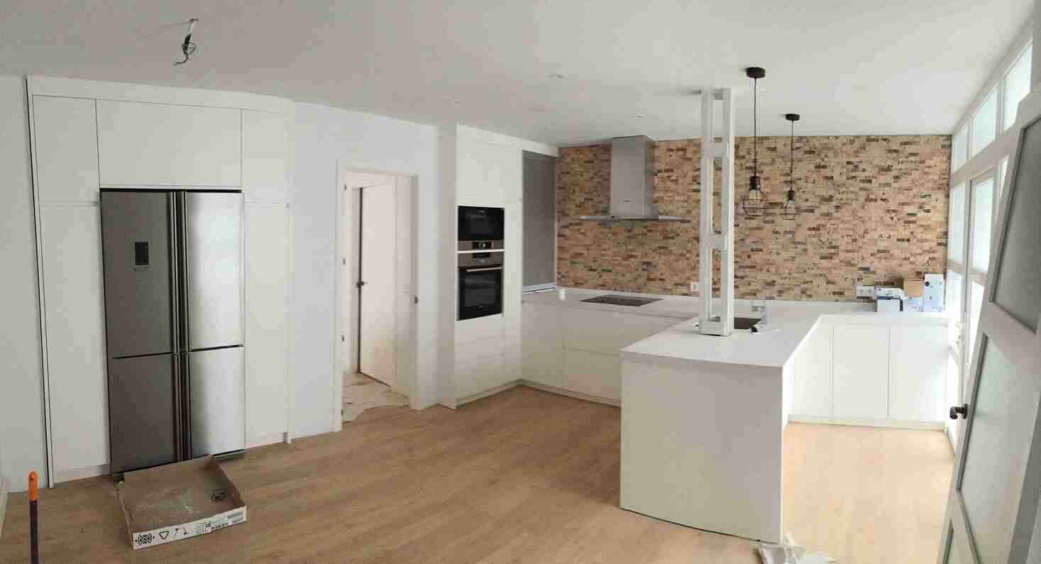 Una cocina con gabinetes blancos y un refrigerador de acero inoxidable.