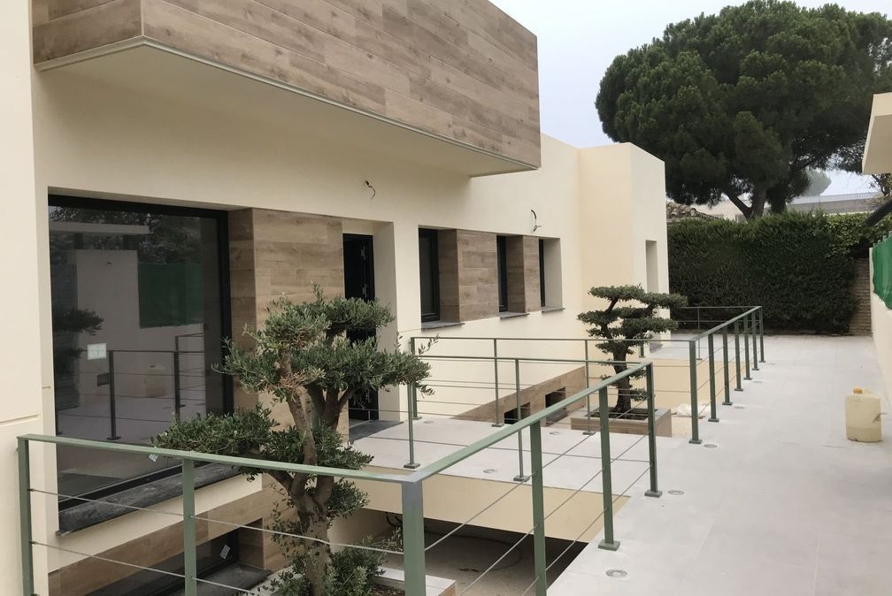 Una casa con un balcón y un árbol delante.