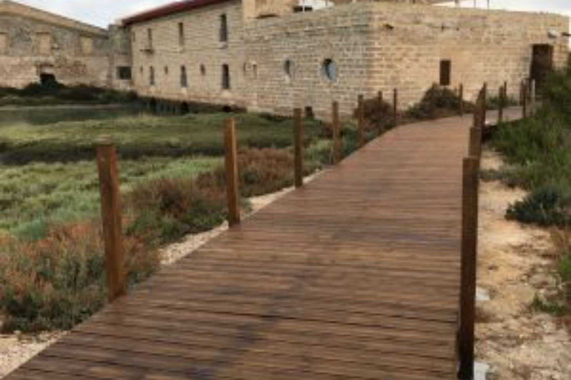 Una pasarela de madera que conduce a un edificio de piedra.