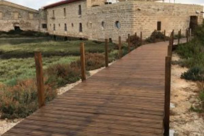 Una pasarela de madera que conduce a un edificio de piedra.
