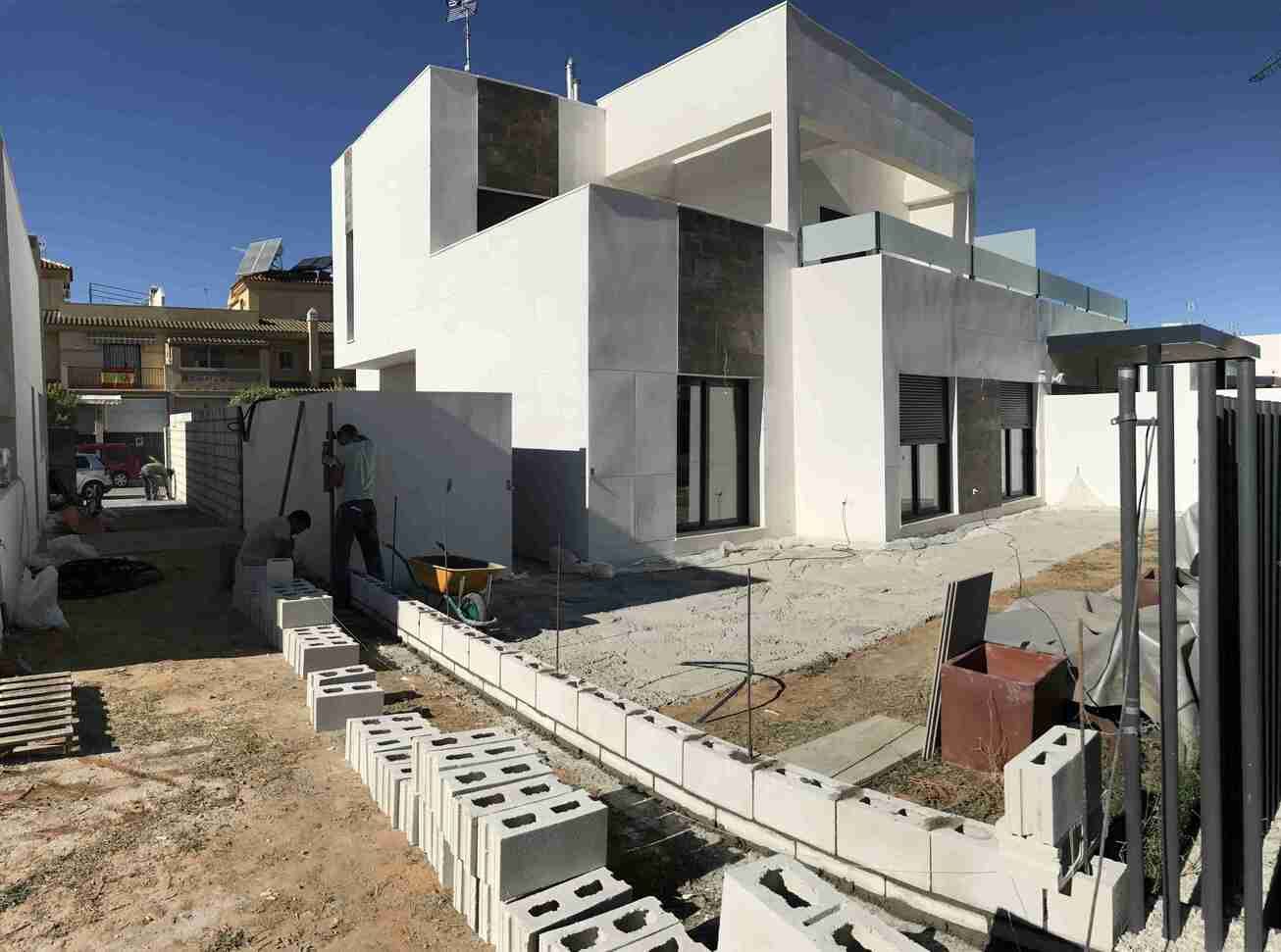 Se está construyendo una gran casa blanca en medio de un campo de tierra.