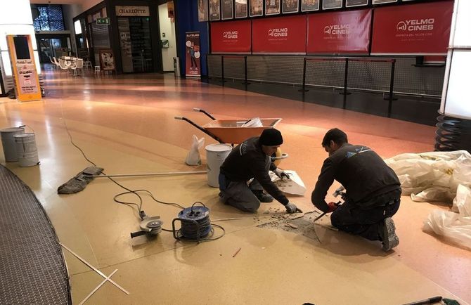 Dos hombres están trabajando en el piso de un edificio.