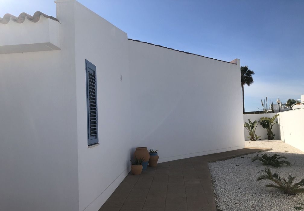 Un edificio blanco con una persiana azul en la ventana.