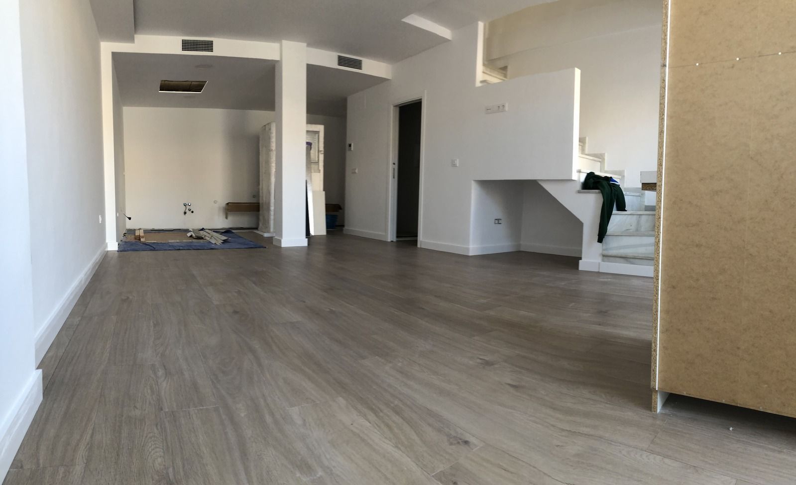 Una gran habitación vacía con suelos de madera y paredes blancas.