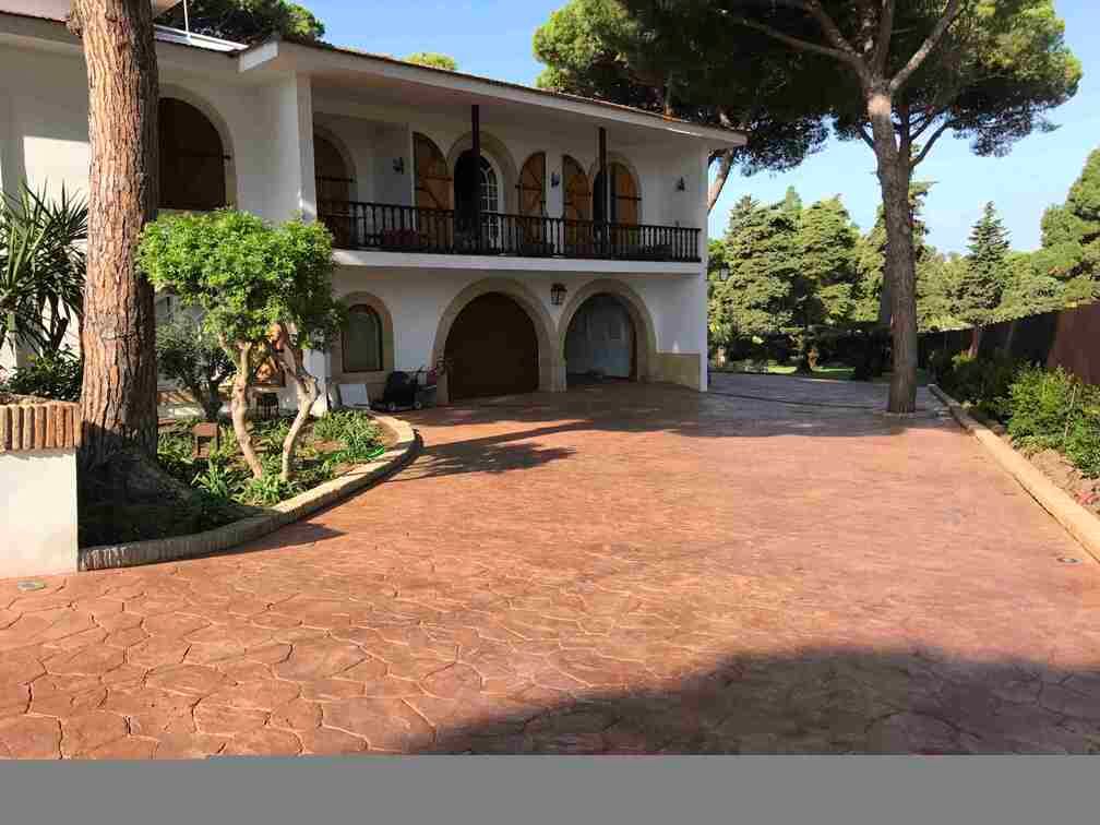 Una gran casa blanca con un gran camino de entrada al frente, rodeado de árboles.