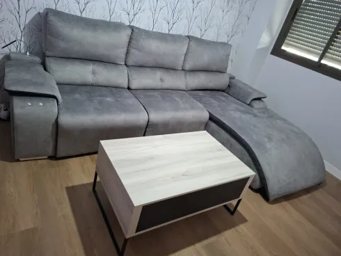 Sofá seccional gris con chaise longue y una mesa de centro blanca en una sala de estar moderna.