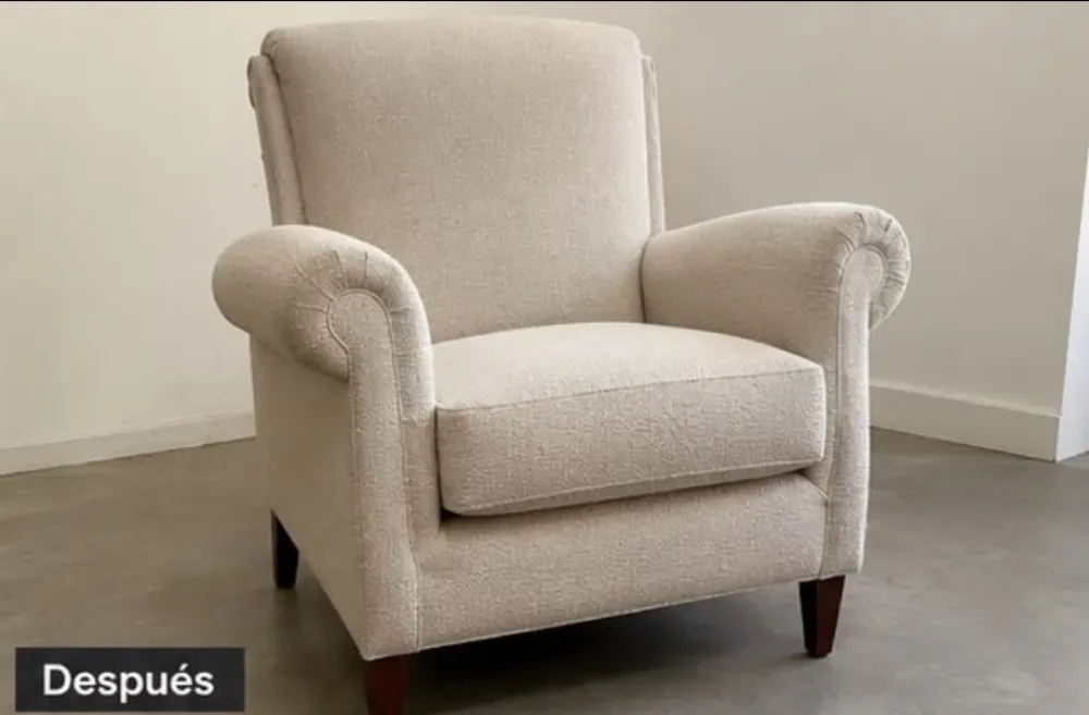 Sillón tapizado en color beige sobre un suelo gris, con la inscripción