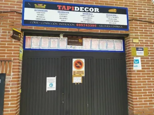 Fachada de un local comercial con puertas negras contraventanas y un letrero azul que dice