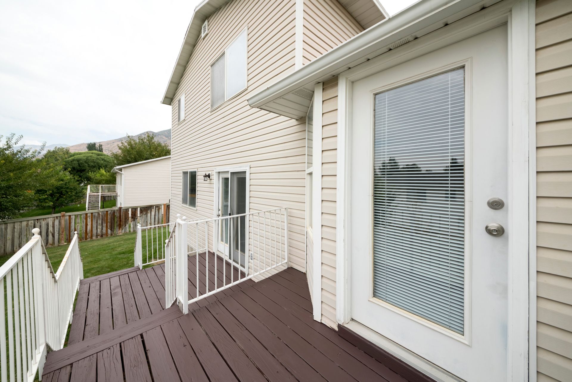 Terrasse arrière d'une maison avec rambarde et sa porte vitrée.